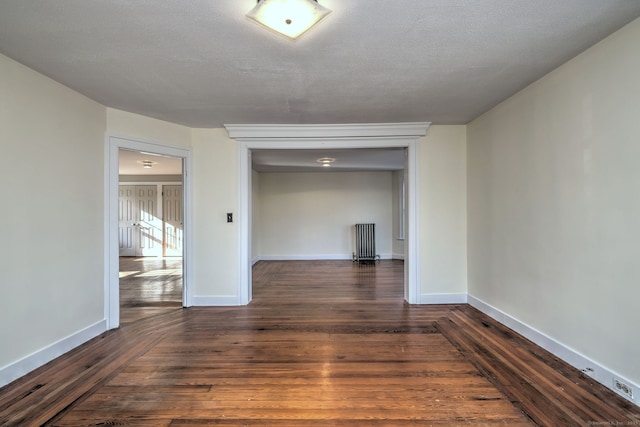 spare room with dark hardwood / wood-style floors, a textured ceiling, and radiator