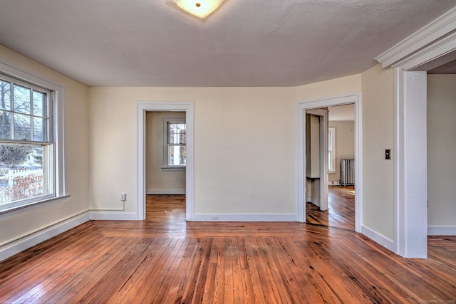 empty room featuring radiator heating unit, a textured ceiling, and hardwood / wood-style flooring