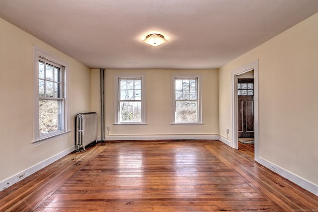 spare room with radiator heating unit and dark hardwood / wood-style floors