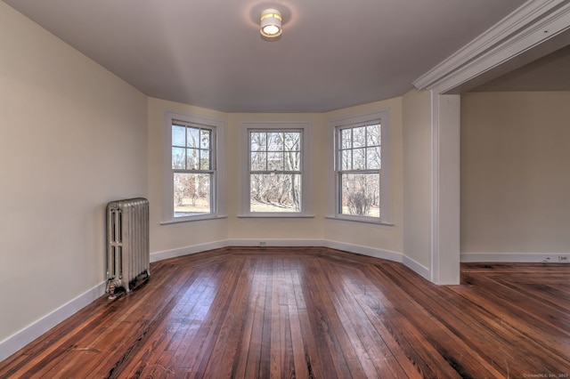 empty room featuring dark hardwood / wood-style flooring and radiator heating unit