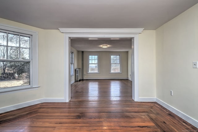 empty room featuring dark hardwood / wood-style flooring and a baseboard heating unit