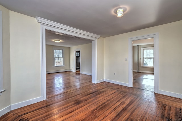 spare room with dark hardwood / wood-style floors, a baseboard radiator, and a healthy amount of sunlight