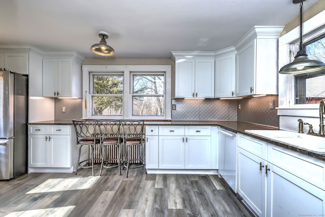 kitchen featuring decorative light fixtures, stainless steel appliances, white cabinetry, and hardwood / wood-style floors