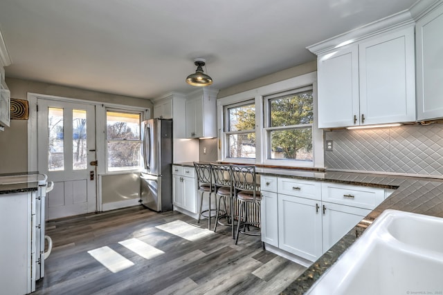 kitchen featuring white cabinetry, a wealth of natural light, stainless steel fridge, and wood-type flooring