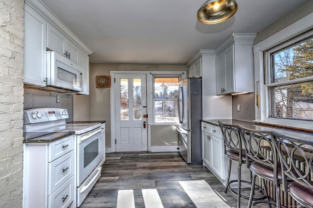 kitchen featuring white appliances, dark hardwood / wood-style floors, white cabinetry, and a wealth of natural light