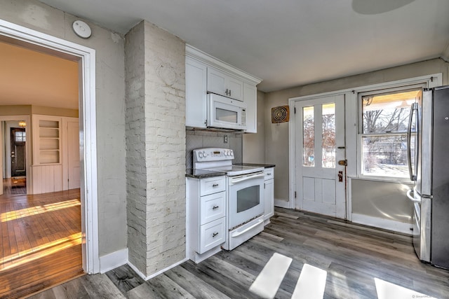 kitchen featuring dark stone counters, white cabinets, dark wood-type flooring, and white appliances