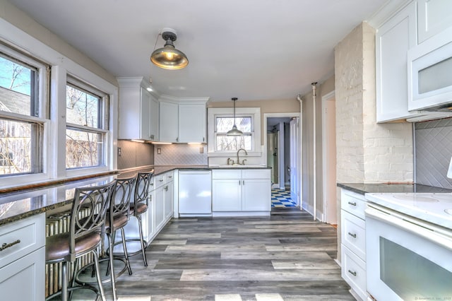 kitchen featuring pendant lighting, white appliances, white cabinetry, and dark stone countertops