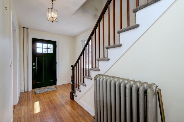 entryway with radiator heating unit, light hardwood / wood-style floors, and an inviting chandelier