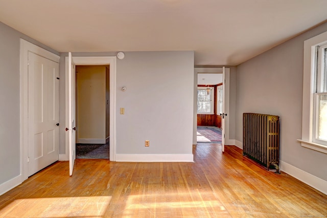 spare room featuring radiator heating unit, a healthy amount of sunlight, and light hardwood / wood-style flooring