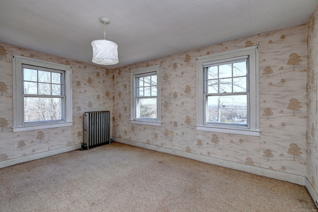 carpeted empty room with radiator heating unit and a textured ceiling