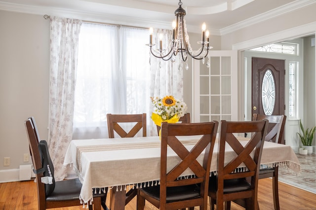 dining area with hardwood / wood-style flooring, a chandelier, a wealth of natural light, and ornamental molding