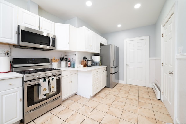 kitchen featuring a baseboard heating unit, white cabinets, appliances with stainless steel finishes, and light tile patterned flooring