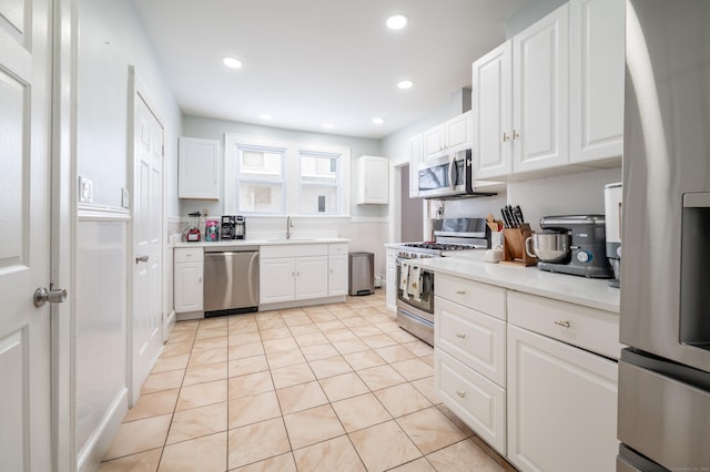 kitchen with sink, white cabinetry, light tile patterned floors, and stainless steel appliances