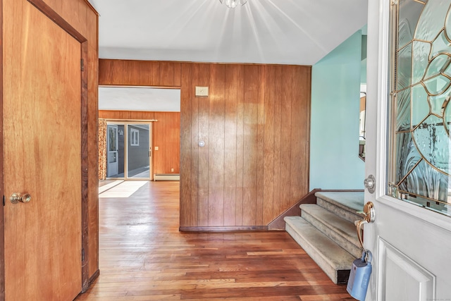 hallway with a baseboard radiator, stairway, wood walls, and hardwood / wood-style flooring