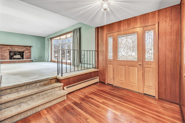 entryway with a baseboard radiator, baseboard heating, wood finished floors, and a fireplace