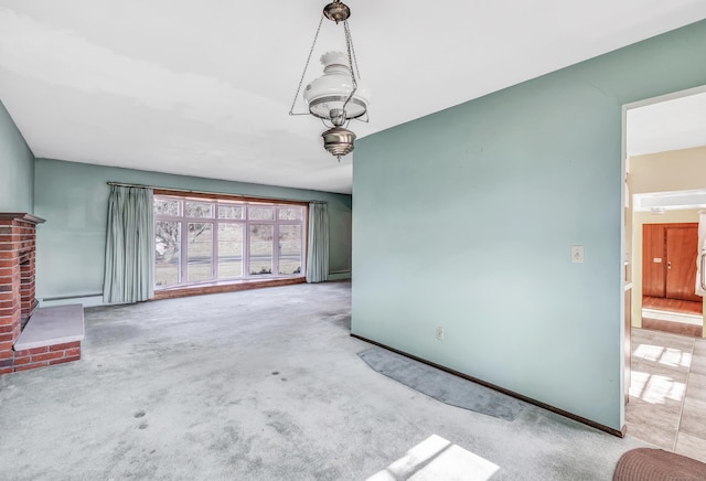 unfurnished living room featuring a brick fireplace, baseboards, and carpet floors