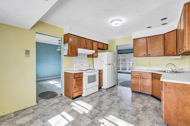 kitchen featuring white appliances, a sink, light countertops, under cabinet range hood, and baseboard heating