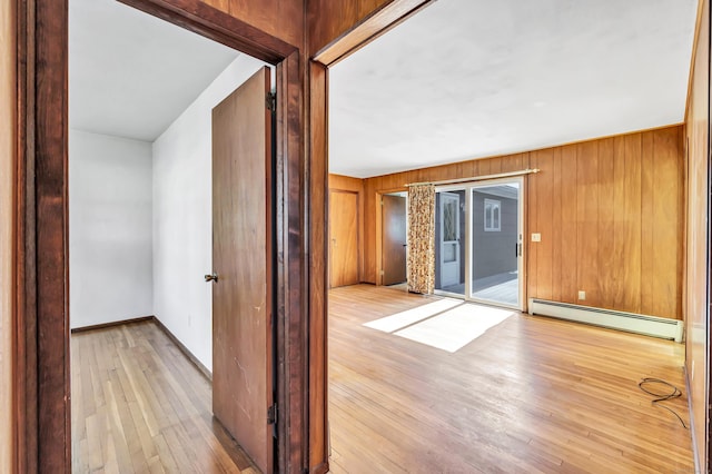 interior space featuring hardwood / wood-style flooring, baseboards, wood walls, and a baseboard radiator