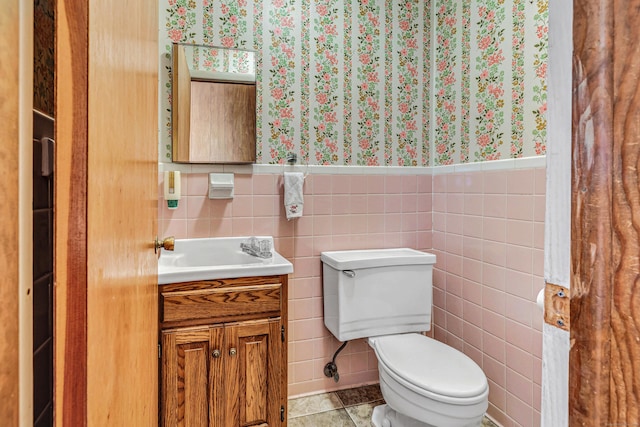 bathroom featuring vanity, a wainscoted wall, wallpapered walls, tile patterned flooring, and toilet