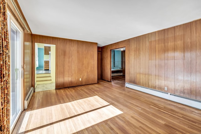 unfurnished room with wood walls, hardwood / wood-style flooring, and a baseboard radiator