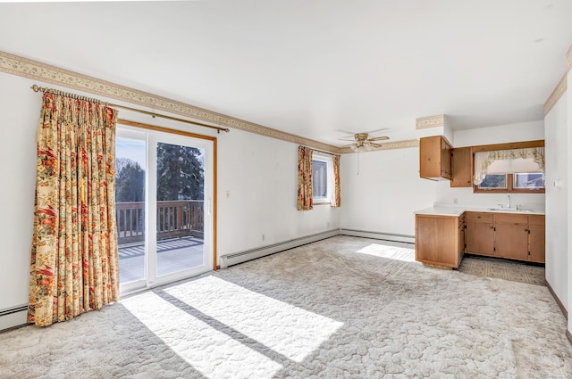 unfurnished living room with a ceiling fan, light colored carpet, baseboard heating, and a sink