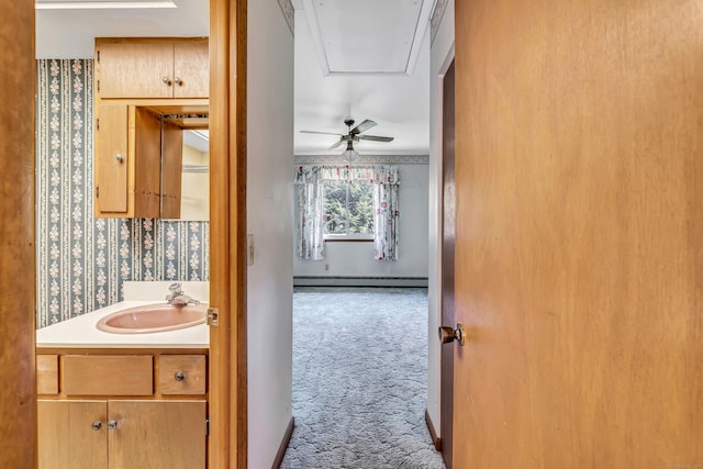 bathroom featuring baseboard heating, wallpapered walls, vanity, and baseboards