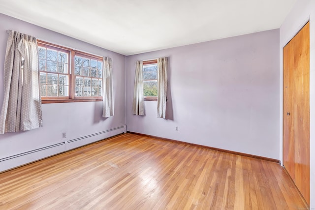 unfurnished room featuring light wood-type flooring, a baseboard radiator, and baseboards