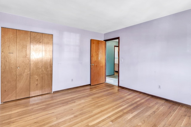 unfurnished bedroom with light wood finished floors, baseboards, and a closet