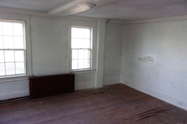 empty room featuring dark hardwood / wood-style floors, plenty of natural light, and radiator heating unit