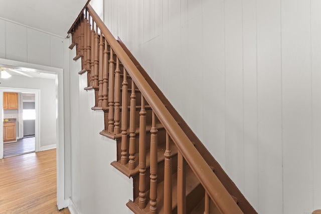 stairs with wooden walls and hardwood / wood-style flooring