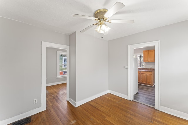 empty room featuring dark hardwood / wood-style floors, ceiling fan, and plenty of natural light