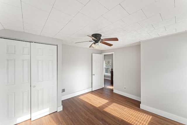 unfurnished bedroom featuring ceiling fan, a closet, and dark wood-type flooring