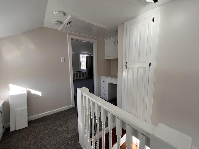 corridor with dark carpet and lofted ceiling