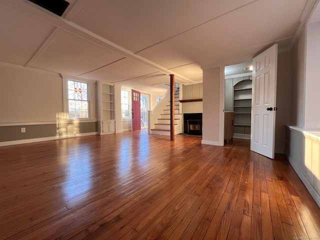 unfurnished living room featuring a brick fireplace, dark hardwood / wood-style floors, and built in features