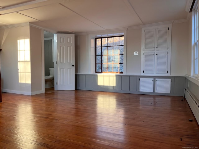 empty room with baseboard heating and hardwood / wood-style flooring