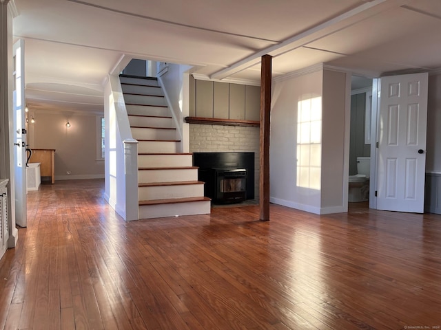 unfurnished living room with a fireplace, wood-type flooring, and ornamental molding