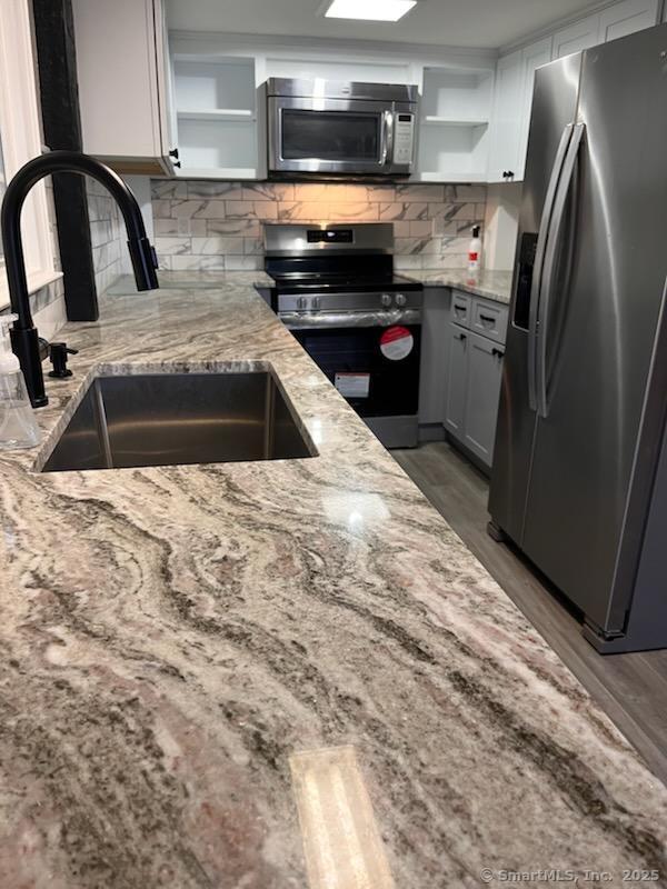 kitchen featuring light stone countertops, sink, appliances with stainless steel finishes, and tasteful backsplash