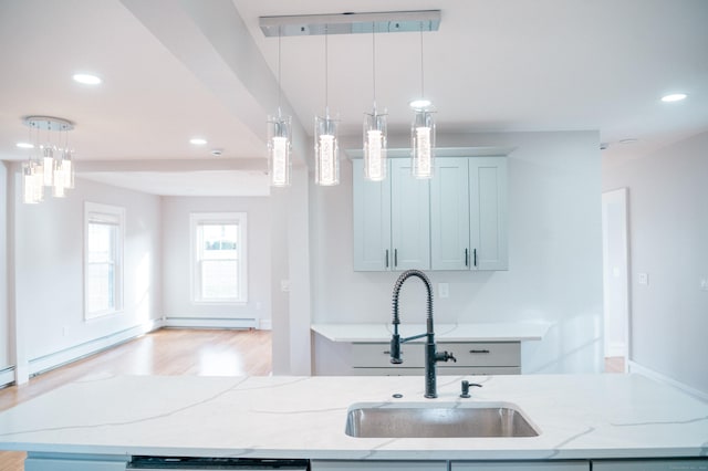 kitchen with light stone counters, recessed lighting, decorative light fixtures, and a sink