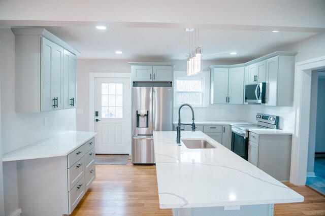 kitchen featuring an island with sink, stainless steel appliances, light hardwood / wood-style flooring, and sink