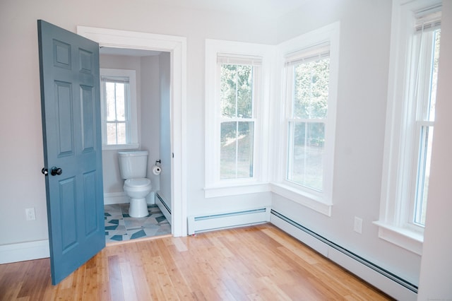 interior space featuring light wood finished floors, baseboards, a baseboard heating unit, and baseboard heating