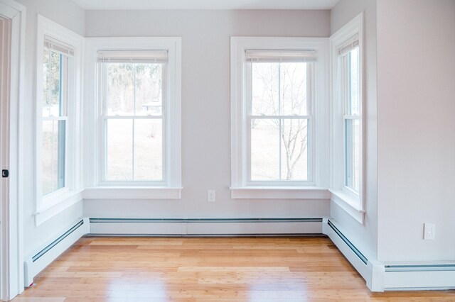 interior space with wood-type flooring and a baseboard heating unit