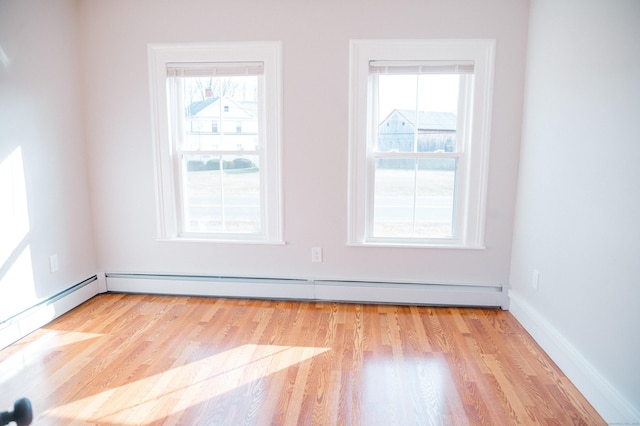 unfurnished room with light hardwood / wood-style floors, baseboard heating, and a healthy amount of sunlight