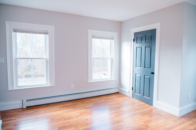 unfurnished room featuring baseboards, a baseboard heating unit, and wood finished floors