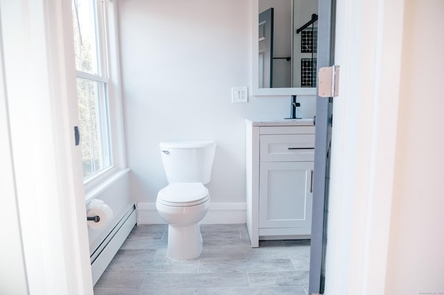 bathroom featuring baseboard heating, vanity, and toilet