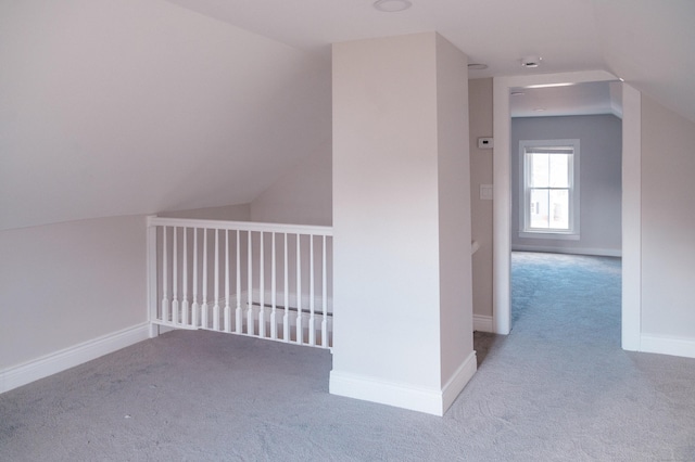 additional living space with light colored carpet and vaulted ceiling