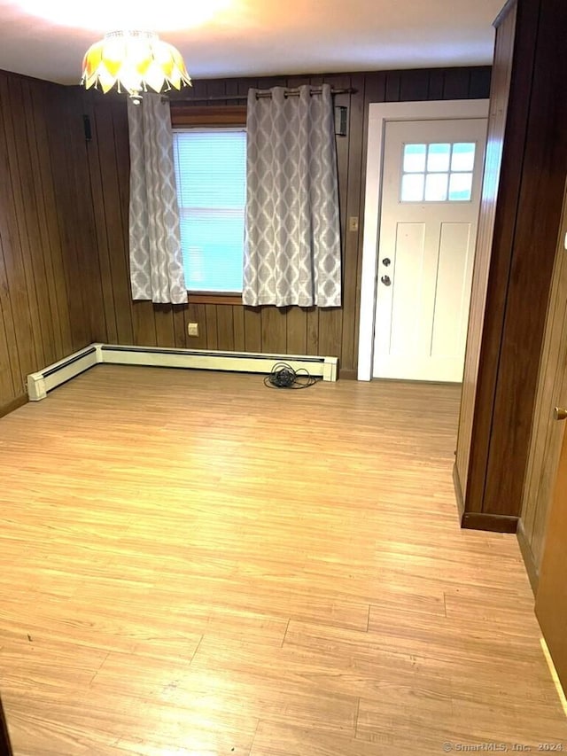 spare room featuring wooden walls, light hardwood / wood-style floors, and a baseboard radiator