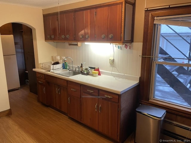 kitchen with light wood-type flooring, white refrigerator, and sink