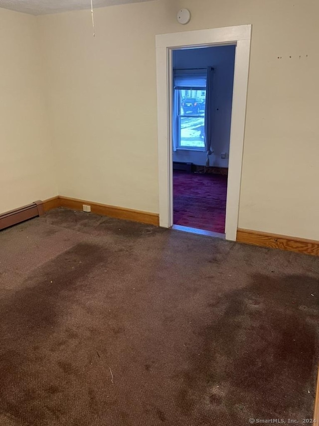 carpeted spare room featuring a baseboard heating unit