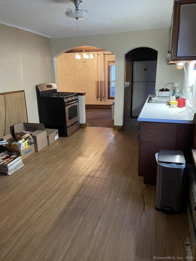 kitchen with dark hardwood / wood-style flooring, stainless steel gas range, dark brown cabinetry, a baseboard radiator, and an inviting chandelier