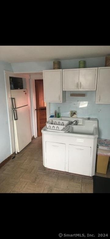 kitchen with white refrigerator and white cabinetry